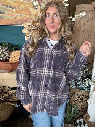 Woman wearing an oversized charcoal, taupe, cream, and brown plaid button-down shirt