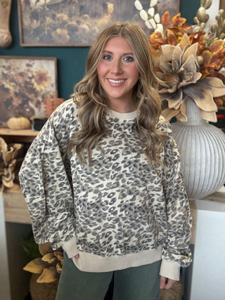 Woman wearing an oatmeal crewneck pullover with gray and taupe leopard print