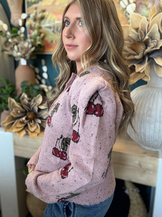 Woman wearing a dusty-pink cherry motif button-front cardigan from Pill Box Boutique