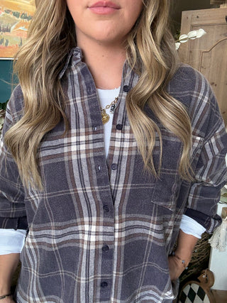 Woman wearing an oversized charcoal, taupe, cream, and brown plaid button-down shirt
