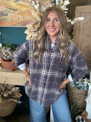 Woman wearing an oversized charcoal, taupe, cream, and brown plaid button-down shirt