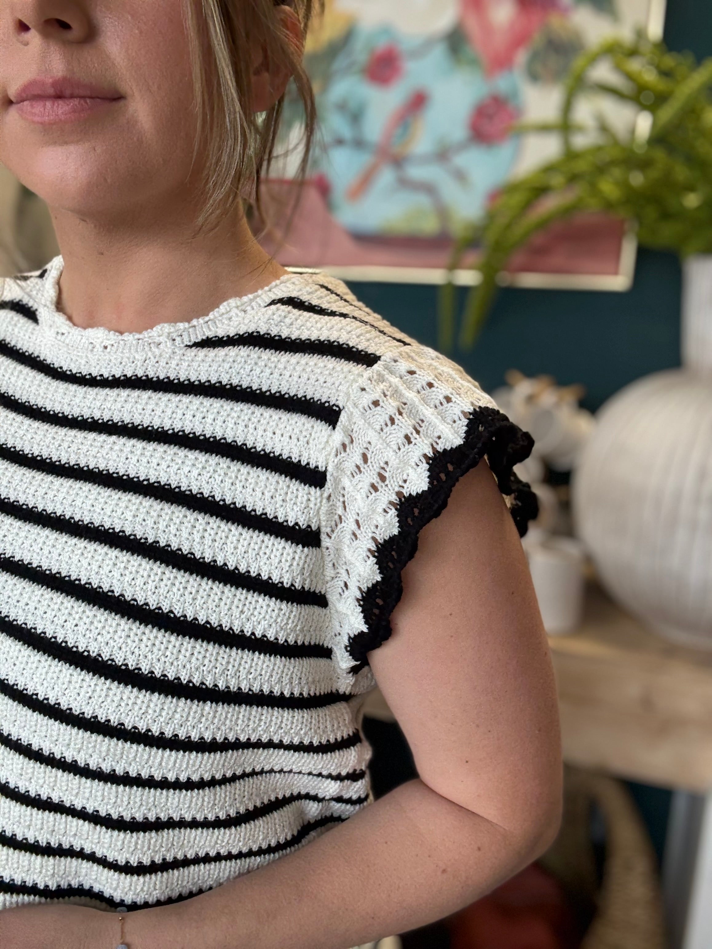 woman wearing black and ivory striped sweater top with crochet ruffle sleeves