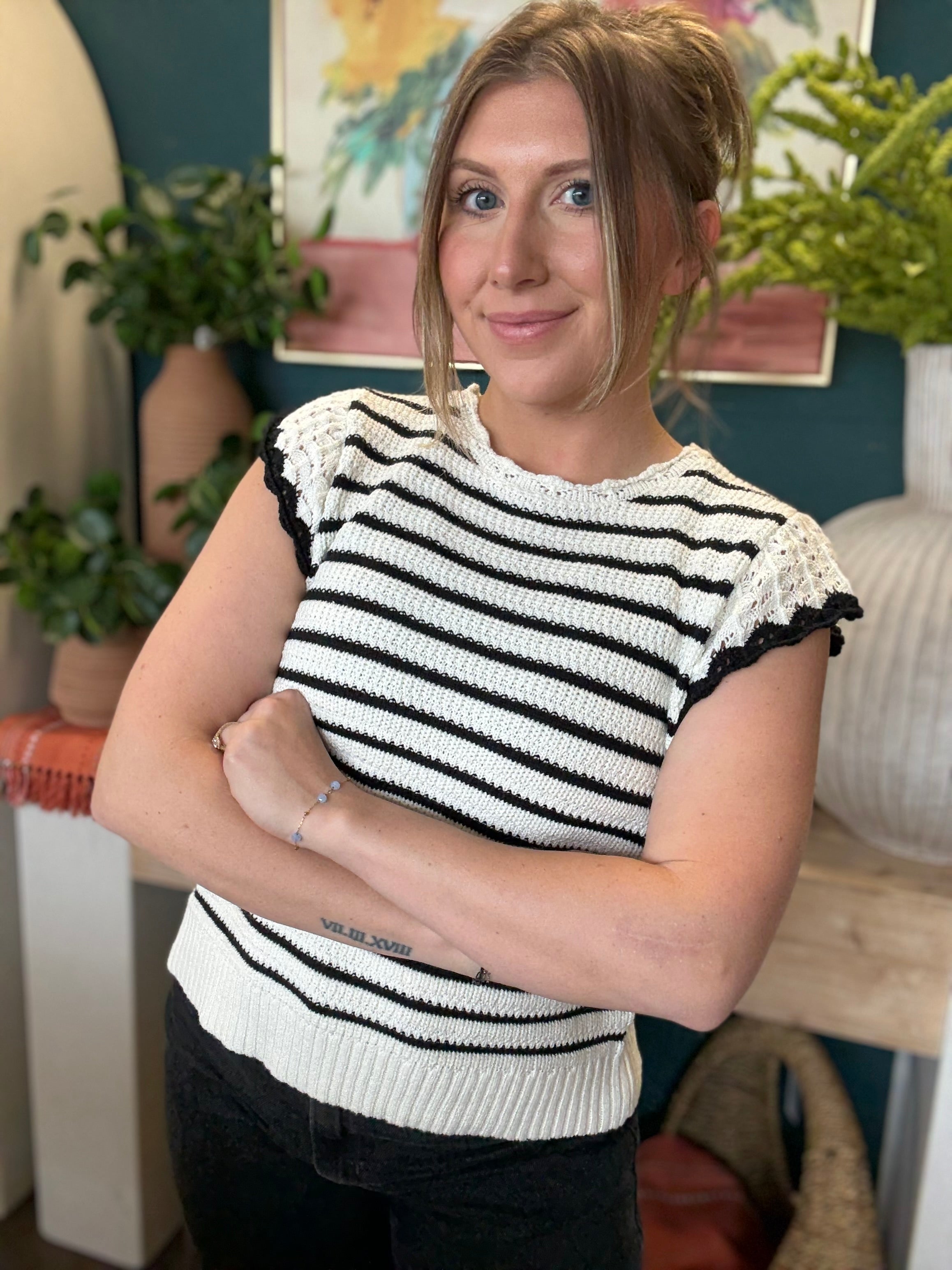 woman wearing black and ivory striped sweater top with crochet ruffle sleeves