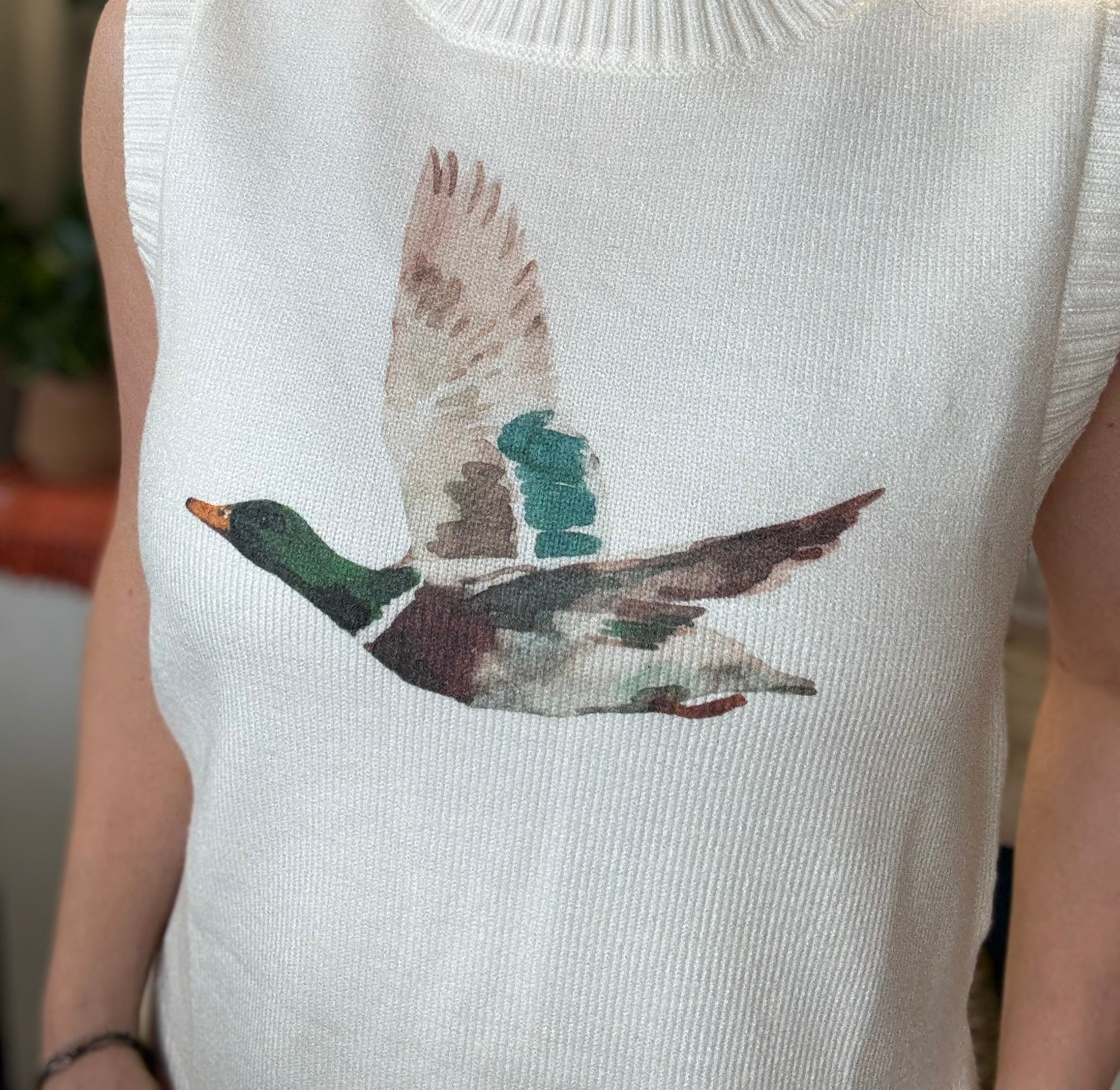 woman wearing ivory sweater vest with flying mallard duck graphic