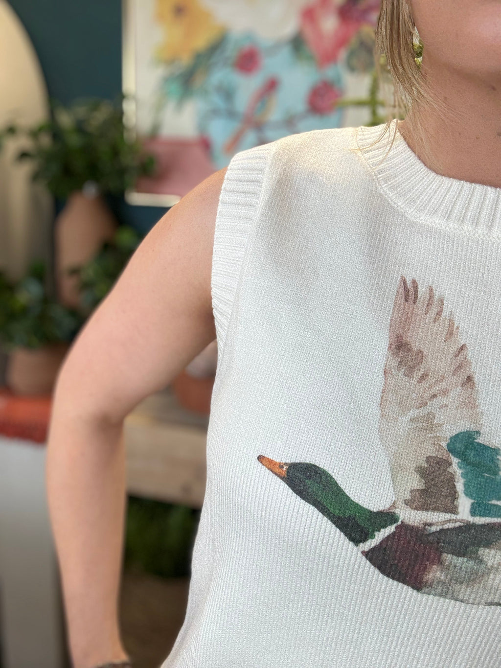 woman wearing ivory sweater vest with flying mallard duck graphic