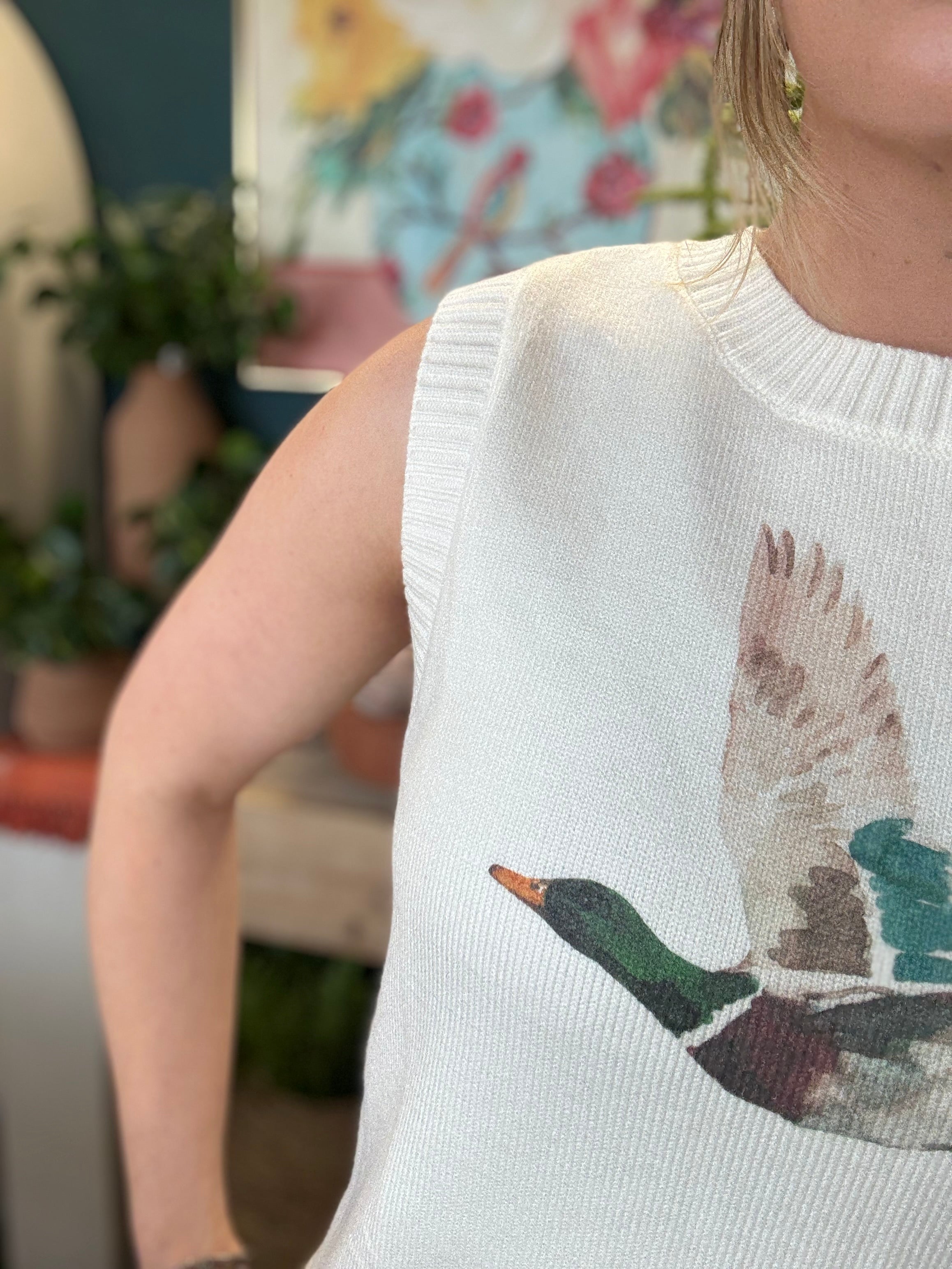 woman wearing ivory sweater vest with flying mallard duck graphic