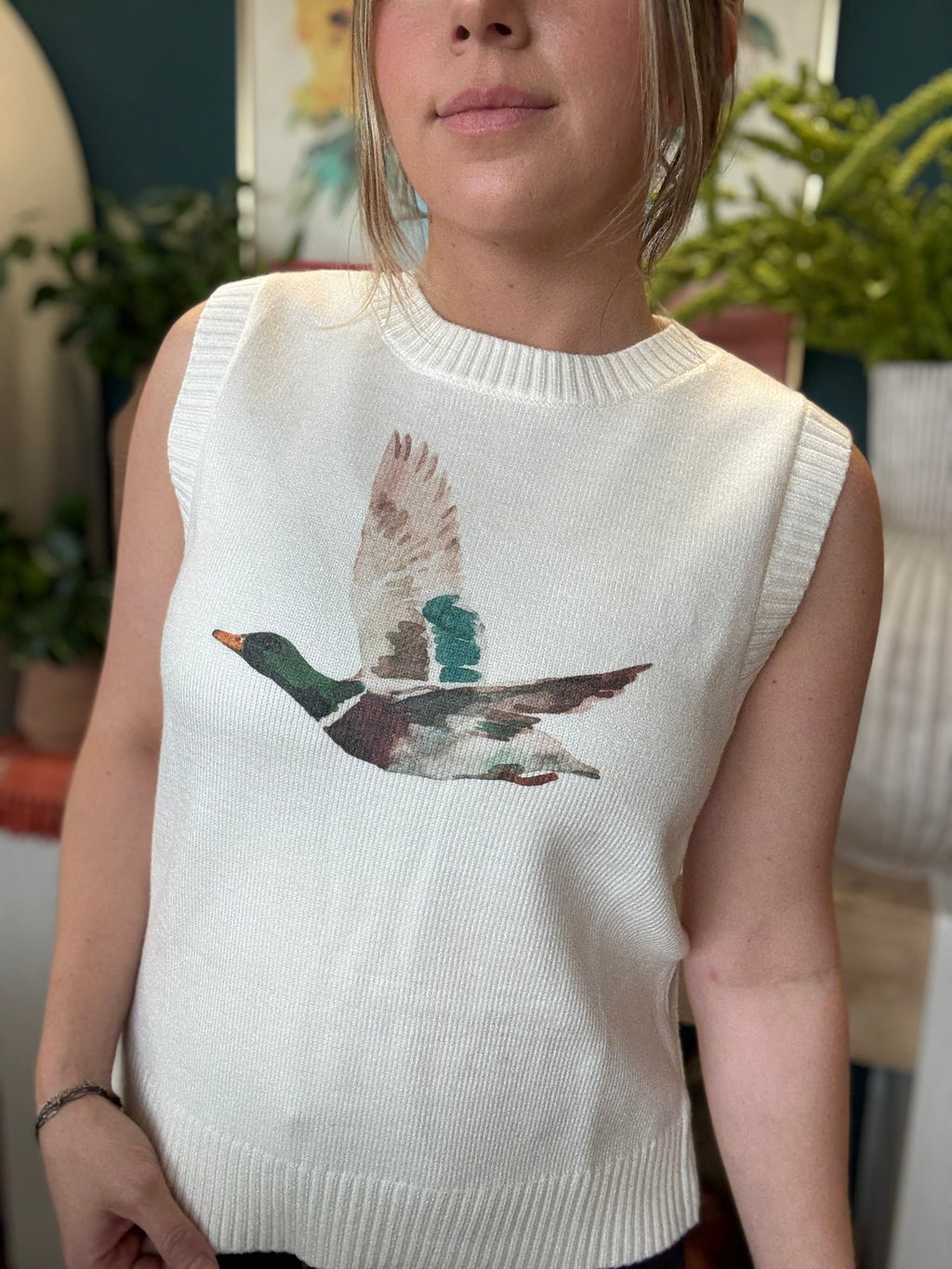 woman wearing ivory sweater vest with flying mallard duck graphic