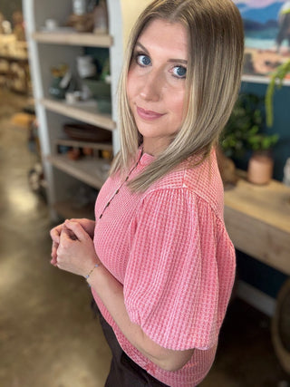 woman wearing coral waffle knit boutique top with puff sleeves and button neckline