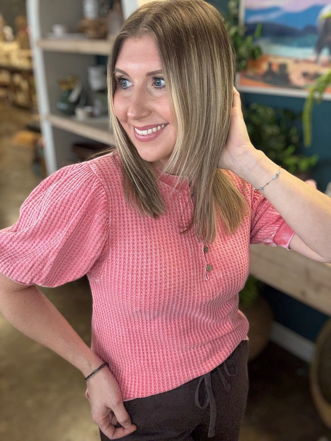woman wearing coral waffle knit boutique top with puff sleeves and button neckline