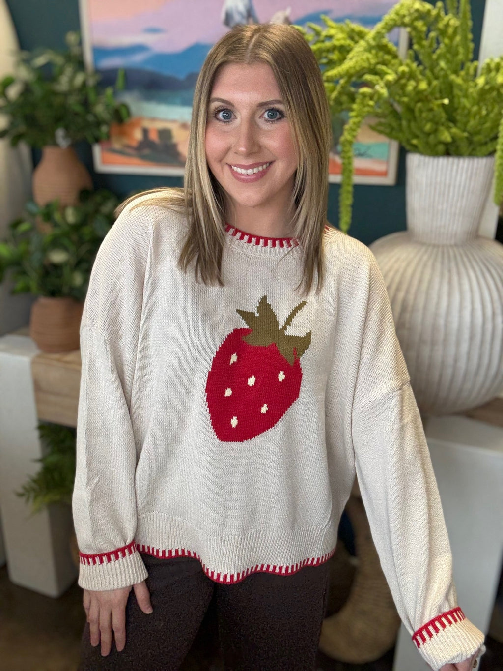 Strawberry graphic knit boutique sweater with contrast stitching styled with casual pants at Pill Box Boutique