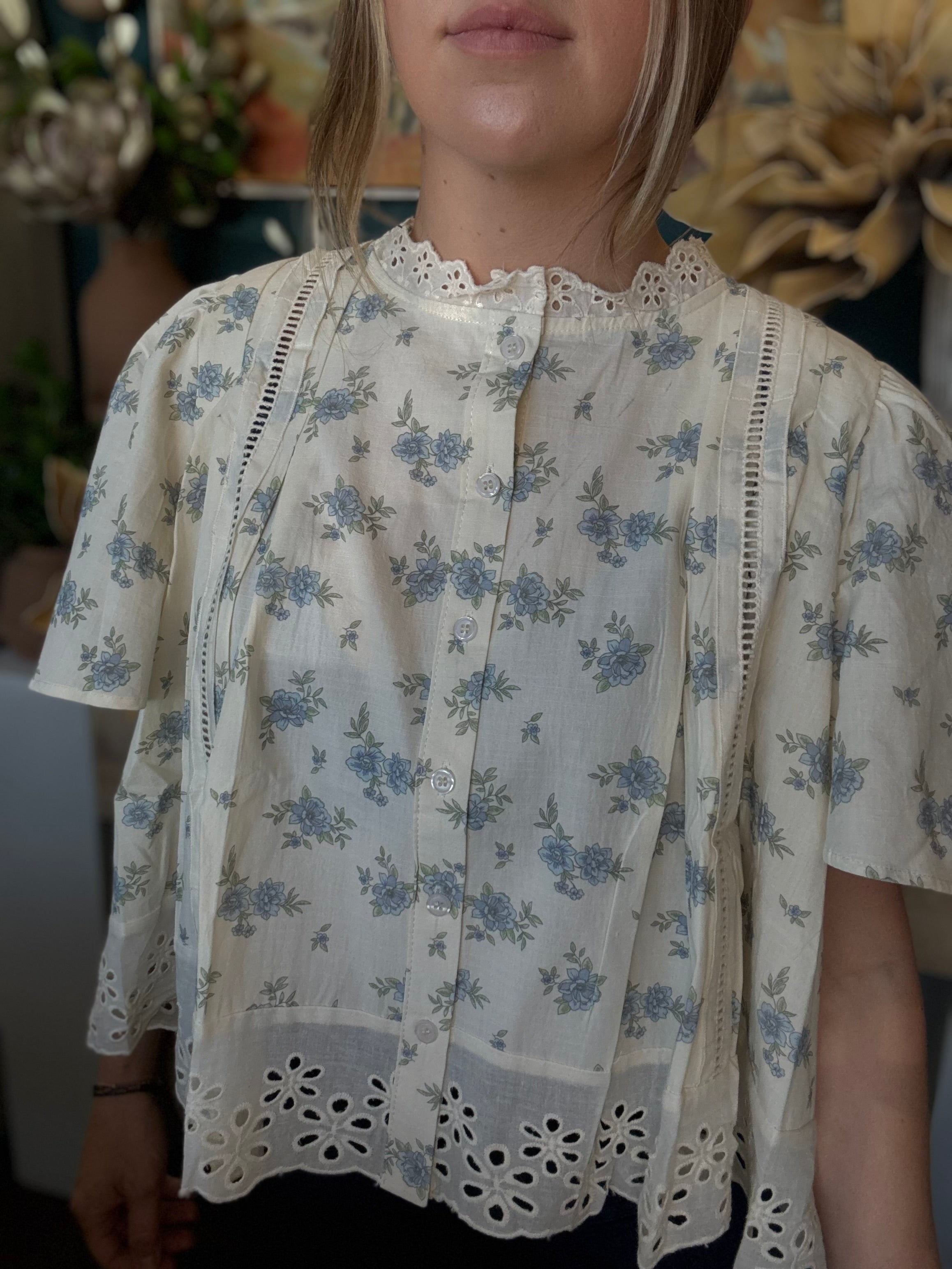 ivory floral blouse with blue flowers lace trim flutter sleeves and eyelet hem detail