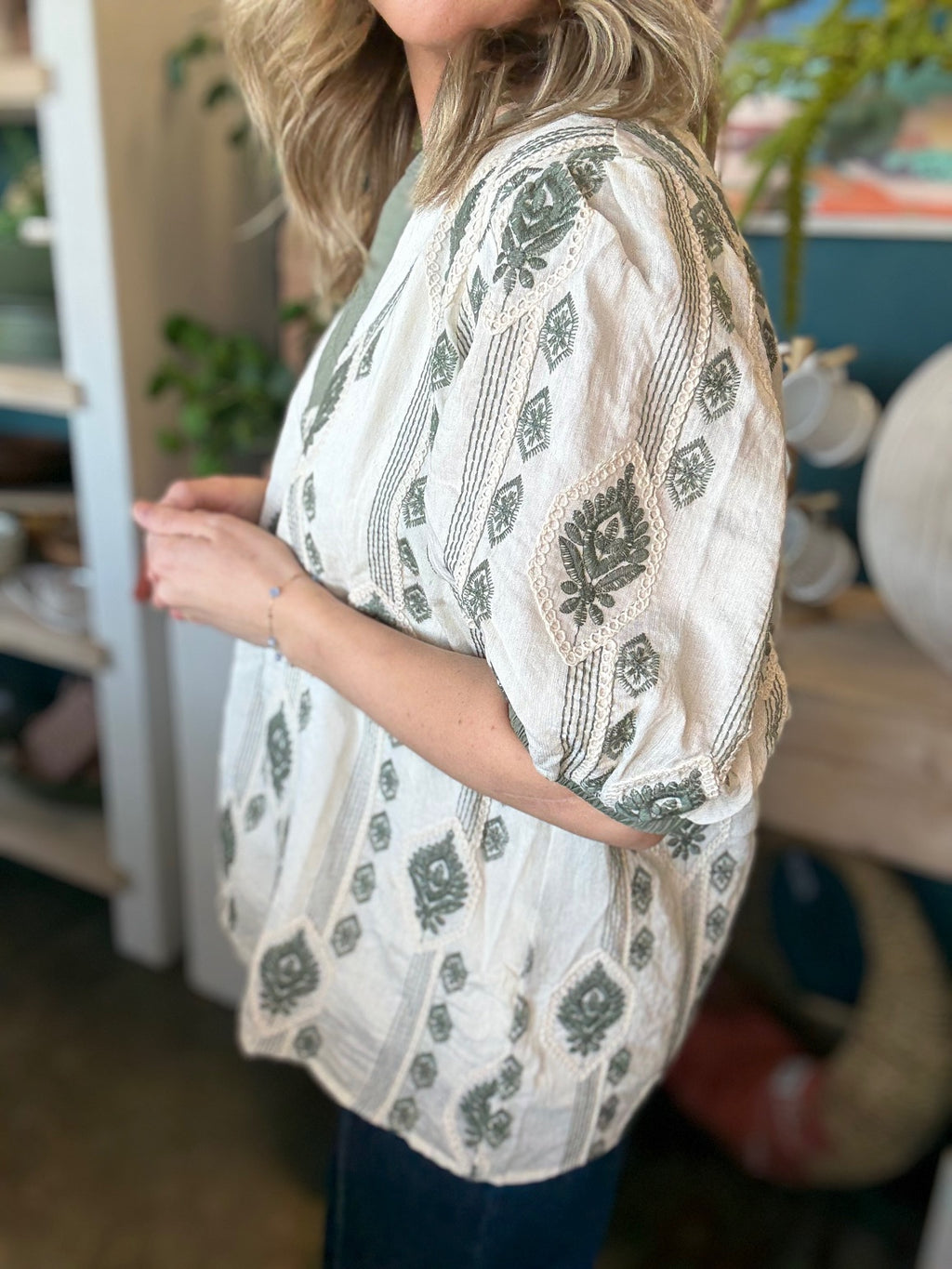 woman wearing ivory and olive printed puff sleeve boutique top with split neckline