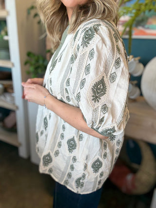 woman wearing ivory and olive printed puff sleeve boutique top with split neckline