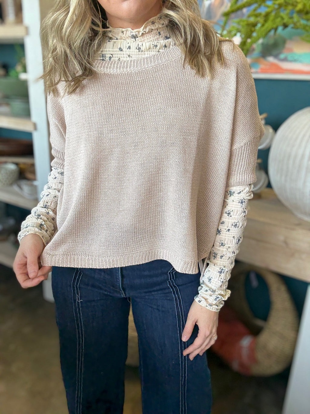 woman wearing oatmeal knit sweater layered over floral textured long sleeve top