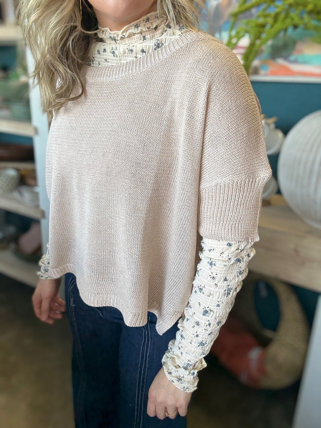 woman wearing oatmeal knit sweater layered over floral textured long sleeve top