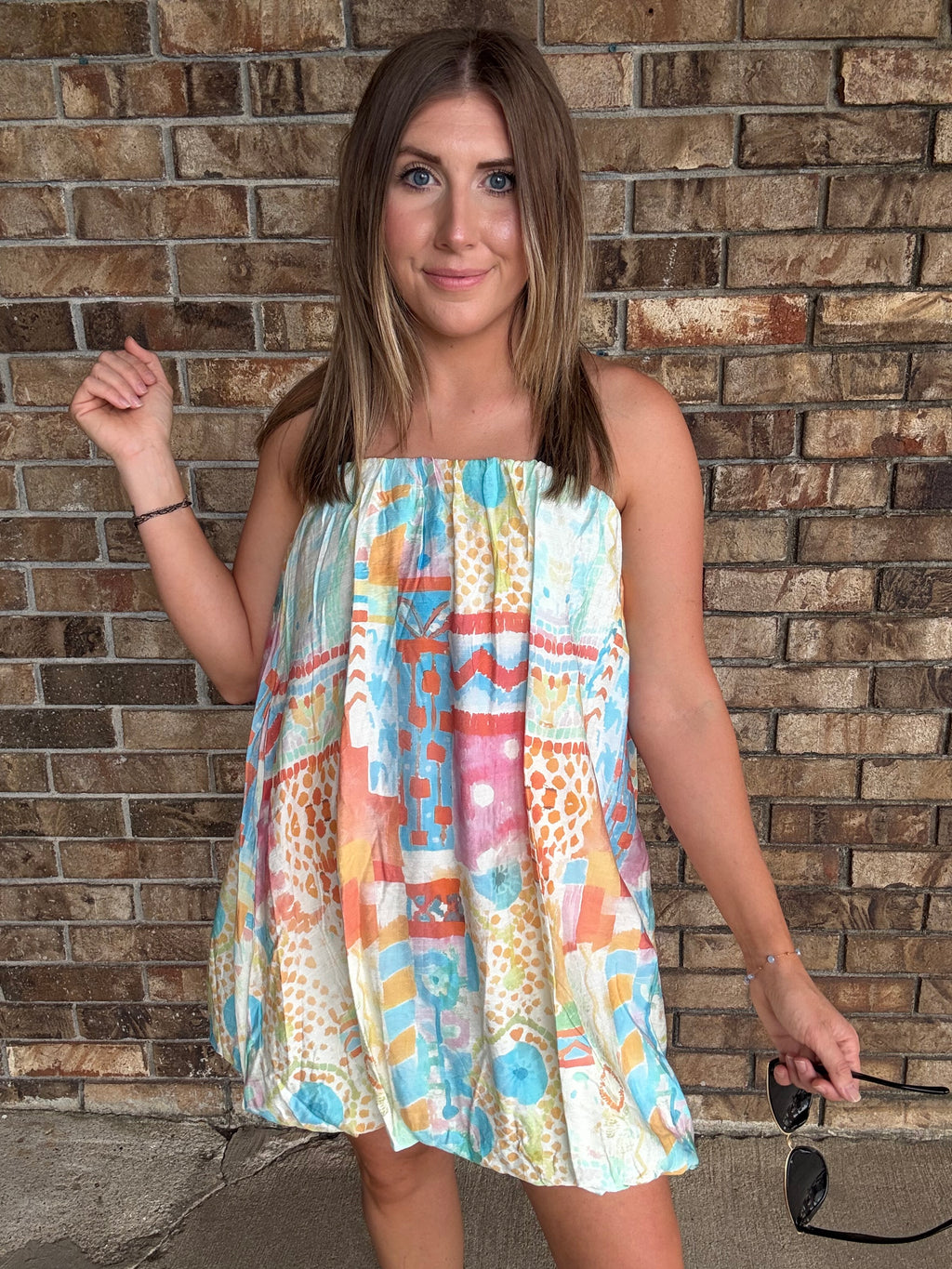 Woman wearing a colorful watercolor tube bubble hem mini dress with a relaxed summer fit