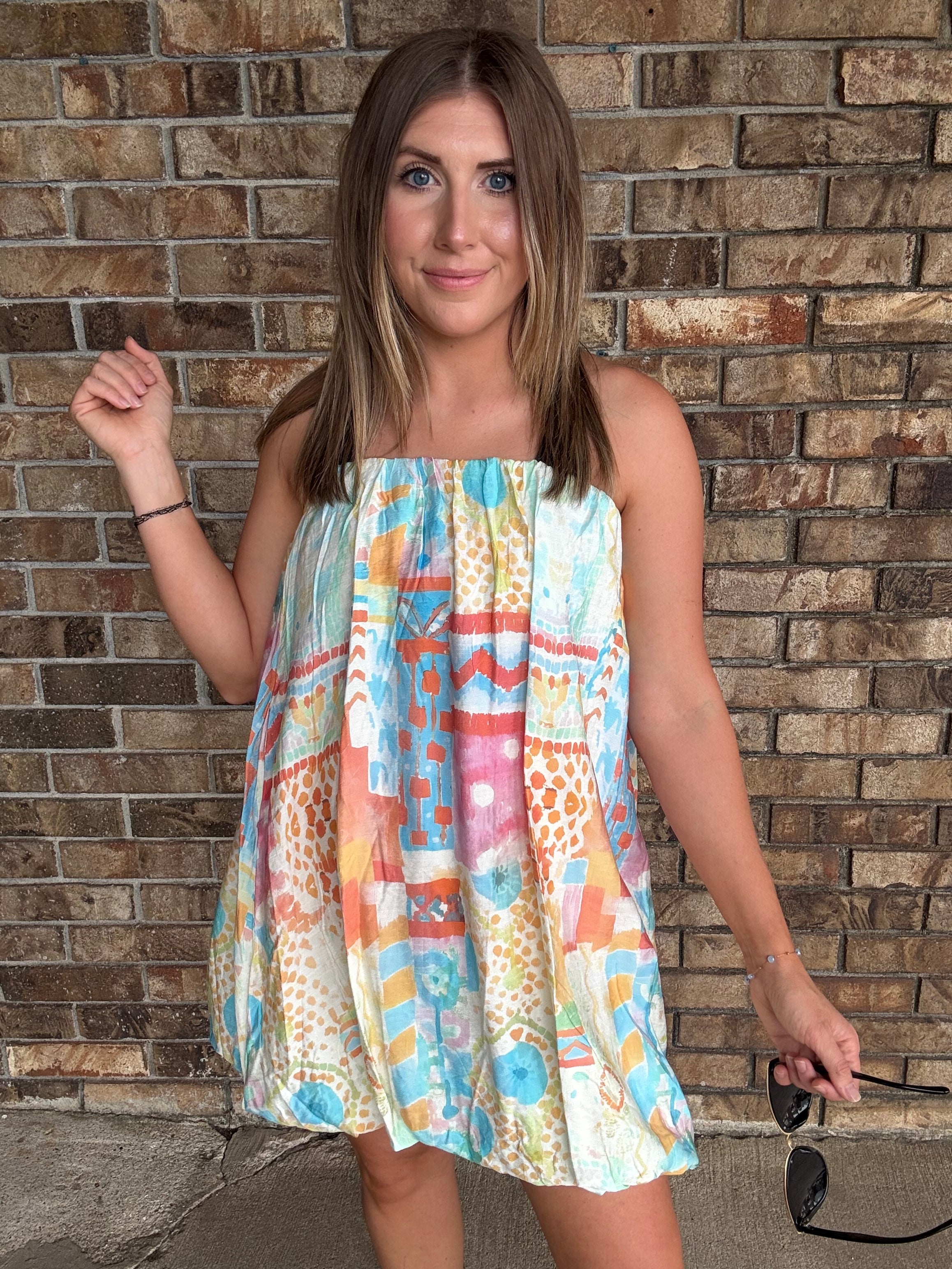 Woman wearing a colorful watercolor tube bubble hem mini dress with a relaxed summer fit