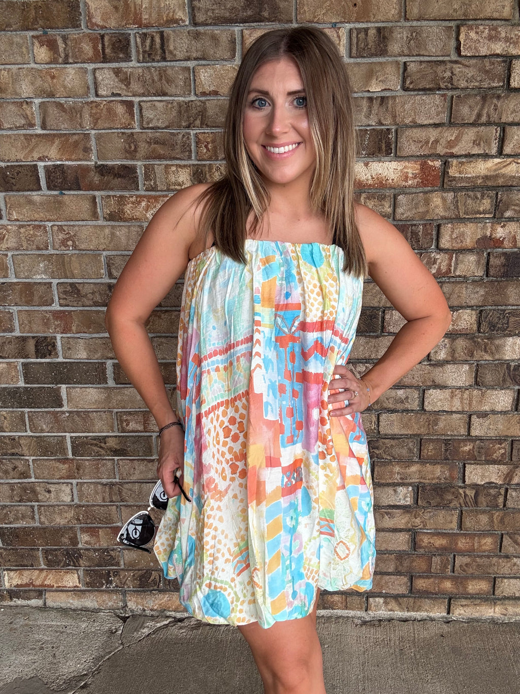 Woman wearing a colorful watercolor tube bubble hem mini dress with a relaxed summer fit