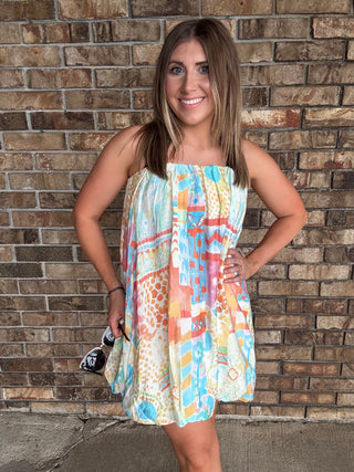 Woman wearing a colorful watercolor tube bubble hem mini dress with a relaxed summer fit