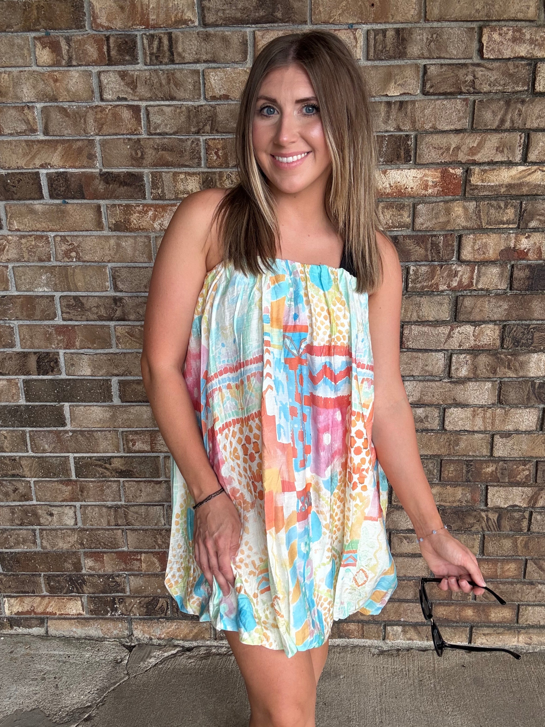 Woman wearing a colorful watercolor tube bubble hem mini dress with a relaxed summer fit