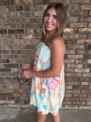 Woman wearing a colorful watercolor tube bubble hem mini dress with a relaxed summer fit