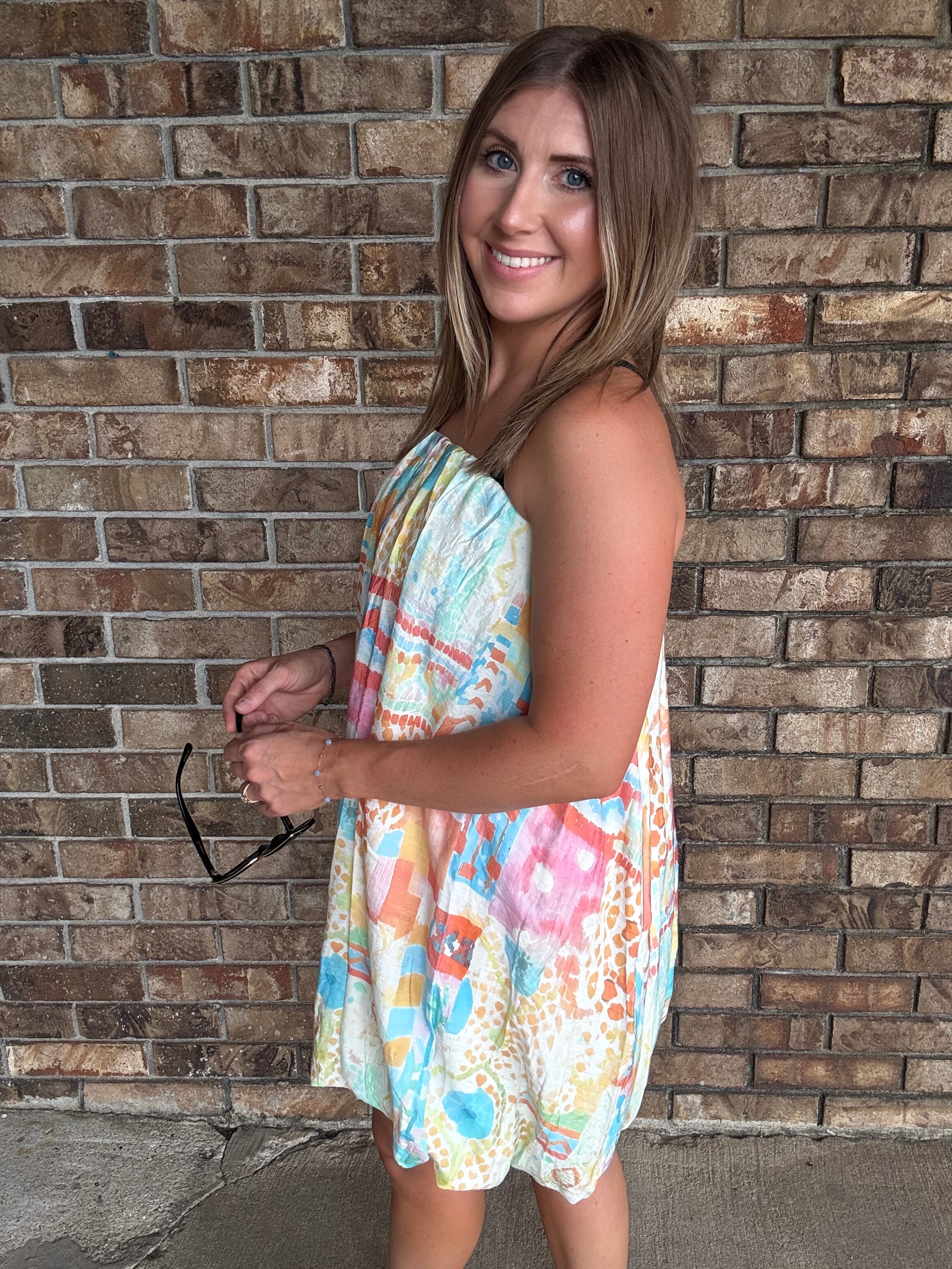 Woman wearing a colorful watercolor tube bubble hem mini dress with a relaxed summer fit