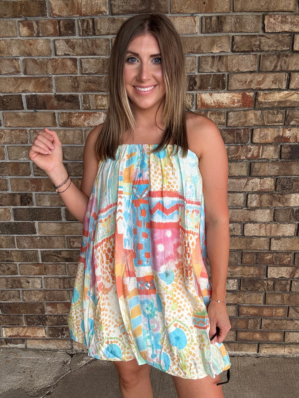 Woman wearing a colorful watercolor tube bubble hem mini dress with a relaxed summer fit