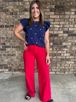 Woman wearing a navy star embroidered ruffle sleeve sweater top with lightweight knit fabric