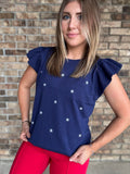 Woman wearing a navy star embroidered ruffle sleeve sweater top with lightweight knit fabric