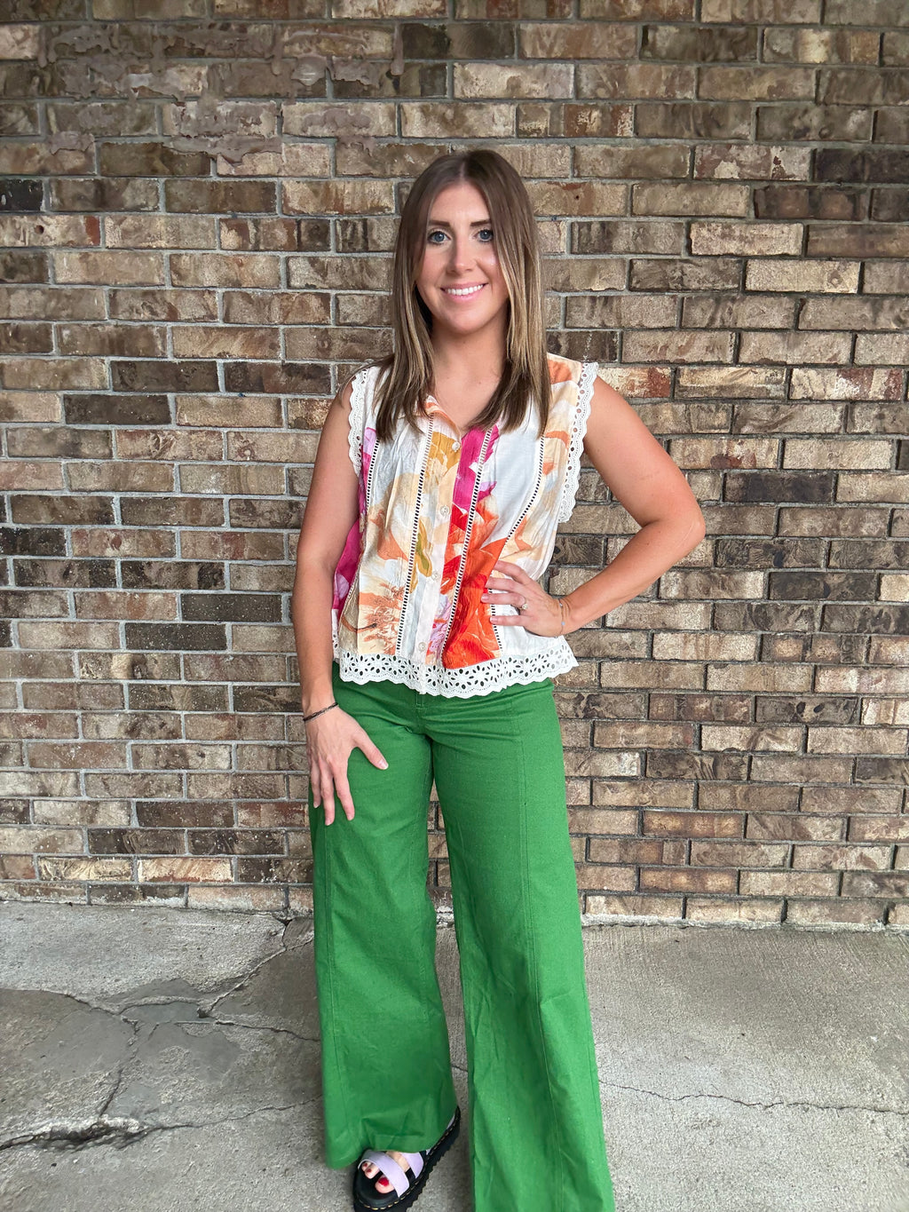 Woman wearing a colorful floral sleeveless blouse with lace trim and button front