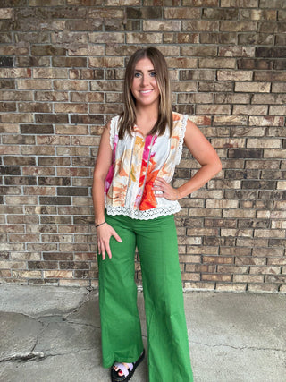 Woman wearing a colorful floral sleeveless blouse with lace trim and button front