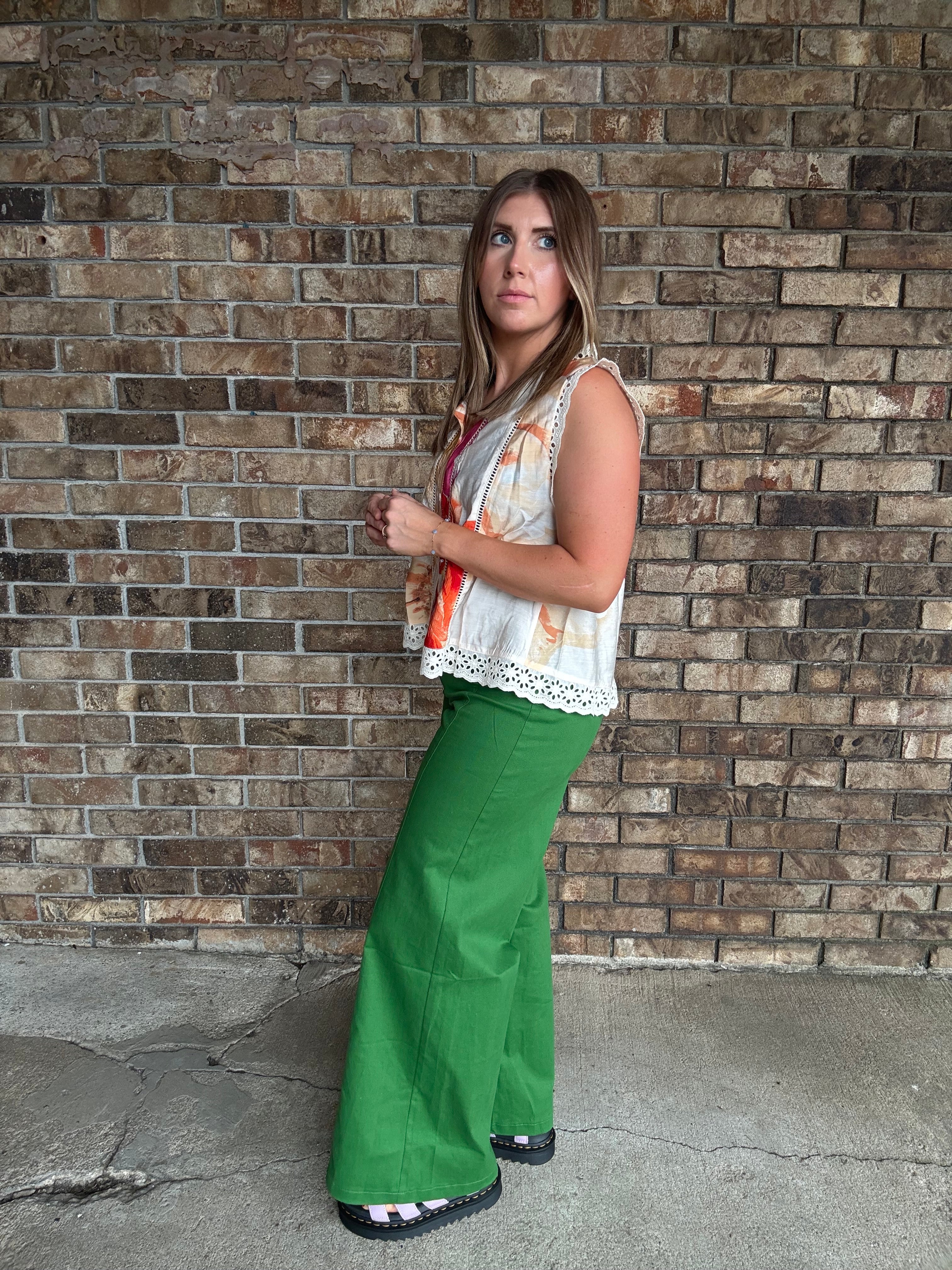 Woman wearing emerald green high-rise wide leg pants styled with a colorful floral sleeveless blouse