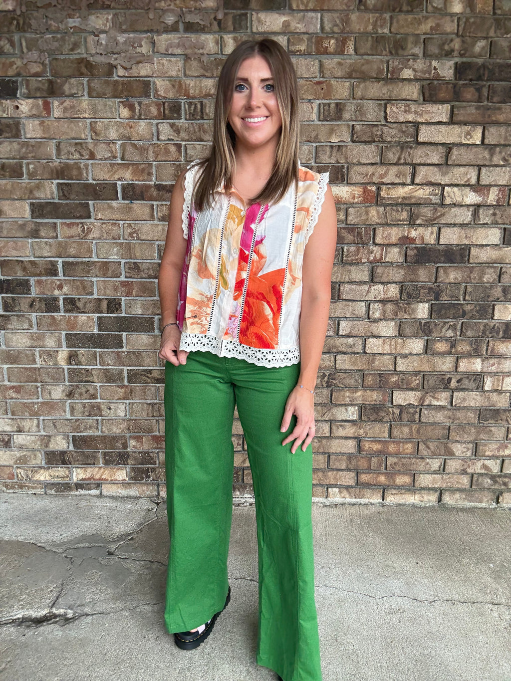 Woman wearing emerald green high-rise wide leg pants styled with a colorful floral sleeveless blouse