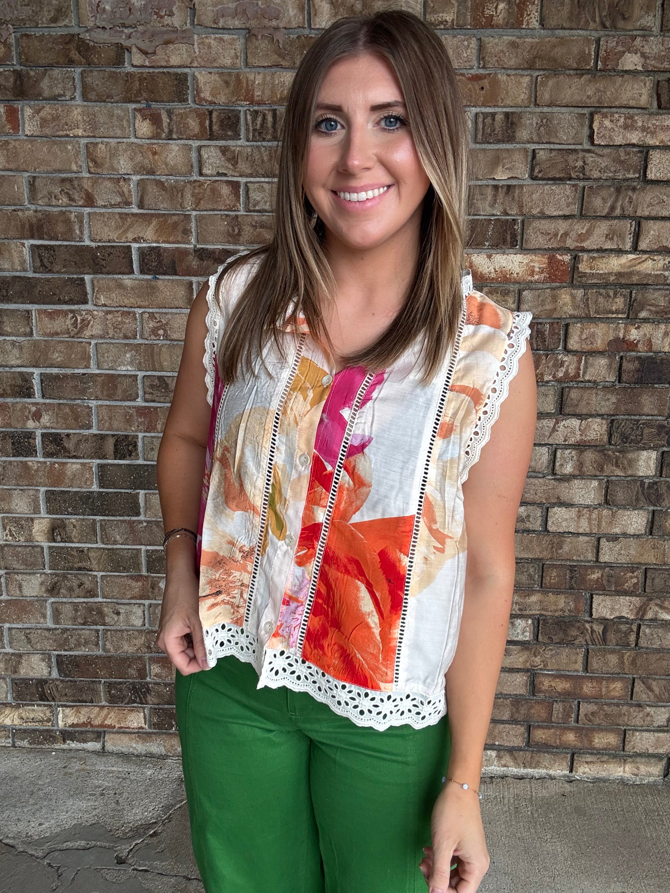 Woman wearing a colorful floral sleeveless blouse with lace trim and button front