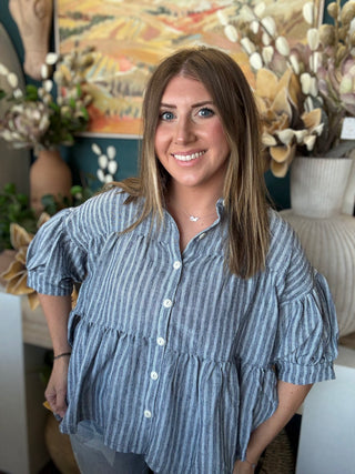 Woman wearing a gray and ivory striped tiered babydoll button-front top with dolman short sleeves