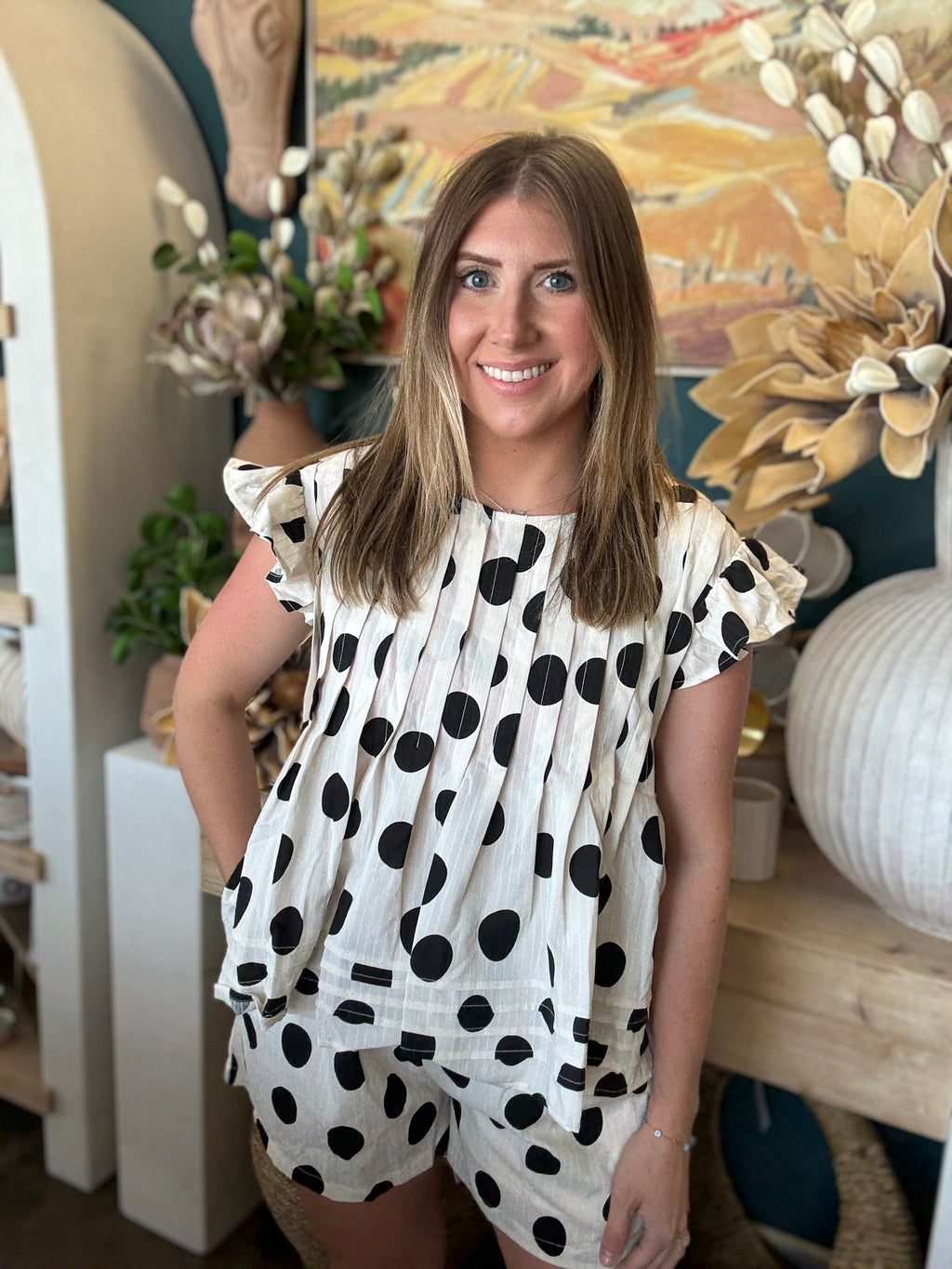 Woman wearing a black and ivory polka dot ruffle sleeve top with matching high-waisted shorts