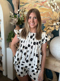 Woman wearing a black and ivory polka dot ruffle sleeve top with matching high-waisted shorts