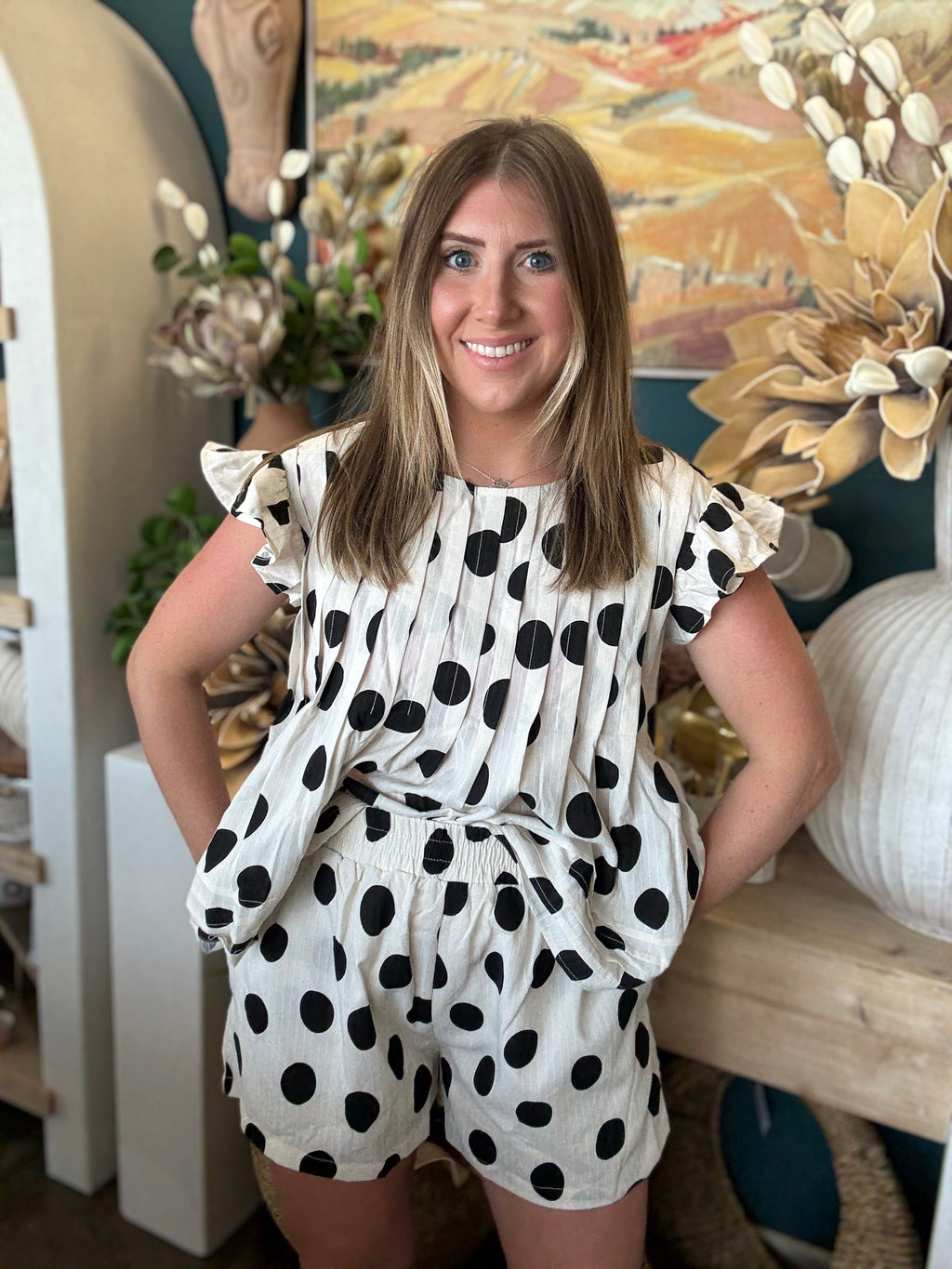Woman wearing a black and ivory polka dot ruffle sleeve top with matching high-waisted shorts