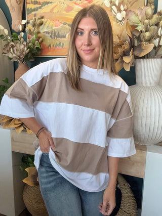 Woman wearing an oversized mocha and white color block short sleeve knit top with light wash jeans