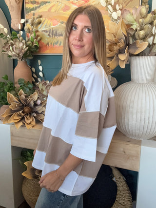 Woman wearing an oversized mocha and white color block short sleeve knit top with light wash jeans