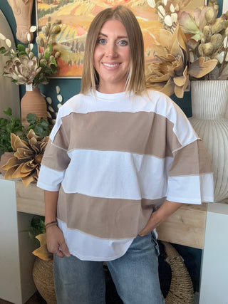 Woman wearing an oversized mocha and white color block short sleeve knit top with light wash jeans