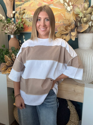 Woman wearing an oversized mocha and white color block short sleeve knit top with light wash jeans