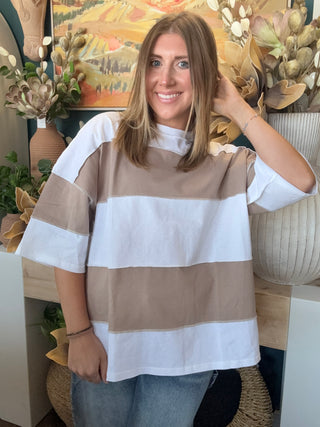Woman wearing an oversized mocha and white color block short sleeve knit top with light wash jeans
