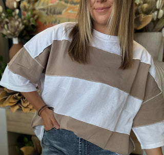 Woman wearing an oversized mocha and white color block short sleeve knit top with light wash jeans