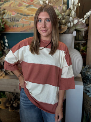 Woman wearing an oversized toasted almond and ivory color block knit top with medium wash jeans