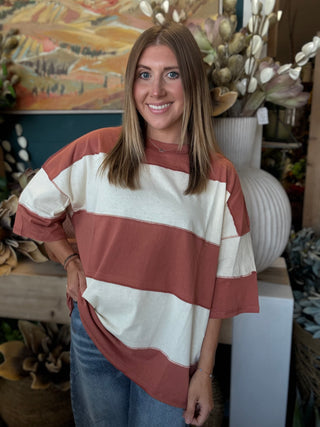 Woman wearing an oversized toasted almond and ivory color block knit top with medium wash jeans