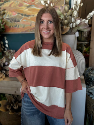 Woman wearing an oversized toasted almond and ivory color block knit top with medium wash jeans