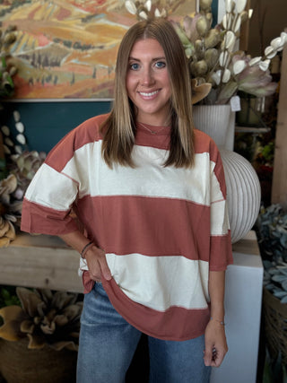 Woman wearing an oversized toasted almond and ivory color block knit top with medium wash jeans