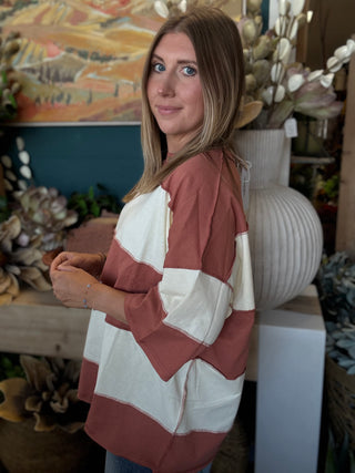 Woman wearing an oversized toasted almond and ivory color block knit top with medium wash jeans