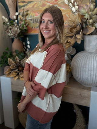 Woman wearing an oversized toasted almond and ivory color block knit top with medium wash jeans